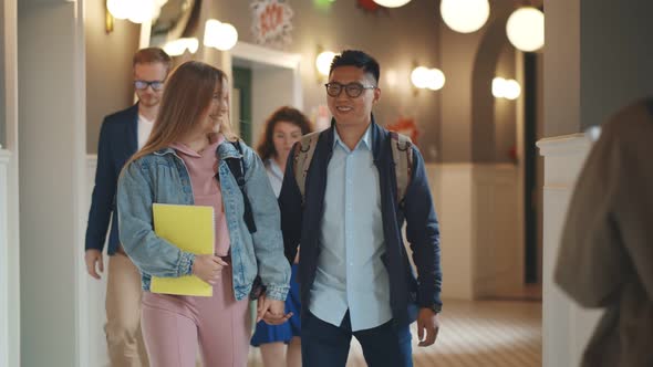 Joyful Multicultural Student Couple Talking Walking on College Corridor