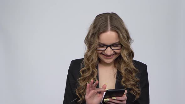 Happy Woman Texting on Her Phone on Gray Background in Studio