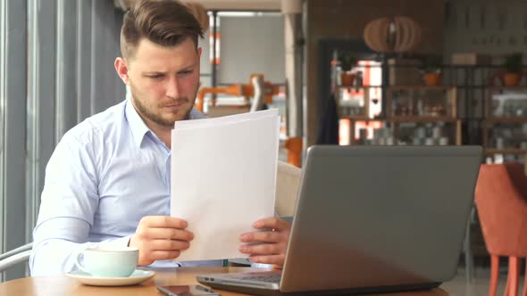 Businessman Looking at Some Papers at the Cafe