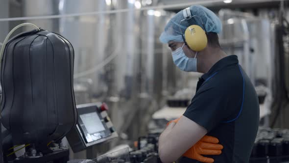 Factory Worker Operating Conveyor With Beer Cans Moving  Medium Shot