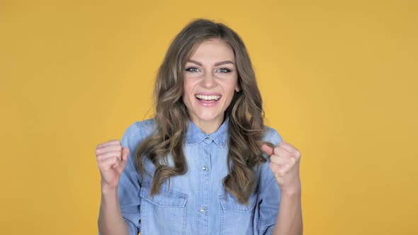 Young Girl Celebrating Success Isolated on Yellow Background