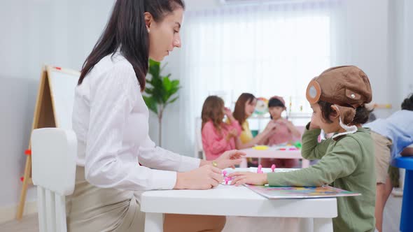 Caucasian beautiful woman teacher teaching a lesson to kid student in classroom at school.