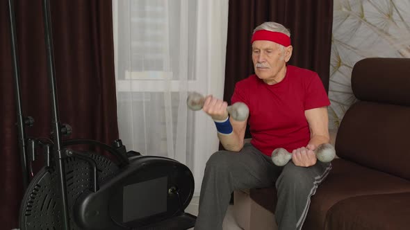 Senior Grandfather Man Doing Weight Lifting Dumbbells Workout Warming Up Exercises in Room at Home