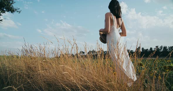 Back View Woman Stands on Agricultural Field in Dress Enjoying Beautiful View