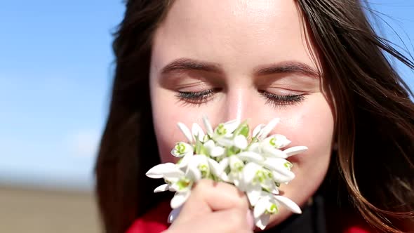 Beautiful Smiling Brunette Girl Holding Bouquet of Snowdrops First Spring Flowers