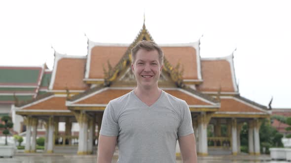Young Happy Tourist Man Smiling Against View of the Buddhist Temple in Bangkok