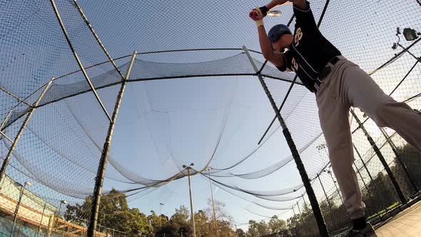 A baseball player practicing at the batting cages.