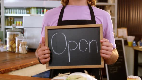 Waiter holding chalkboard with open sign