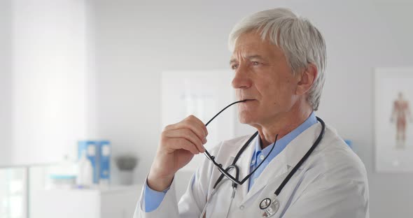 Confident Senior Male Doctor with Stethoscope Standing in Office