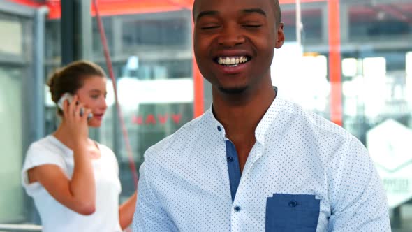 Male business executive smiling at camera while colleague talking on mobile phone