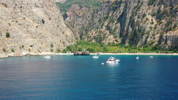 aerial drone flying low to the water as it passes by speed boats and sail boats anchored in the blue