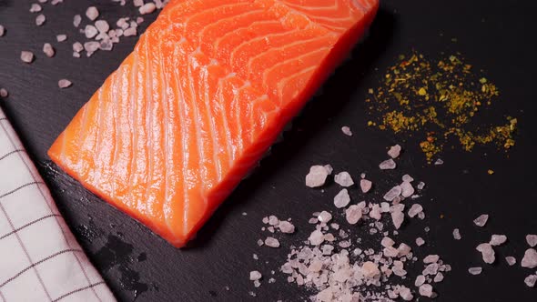 Delicious Fresh Salmon with Salt and Spices on a Black Stone Table