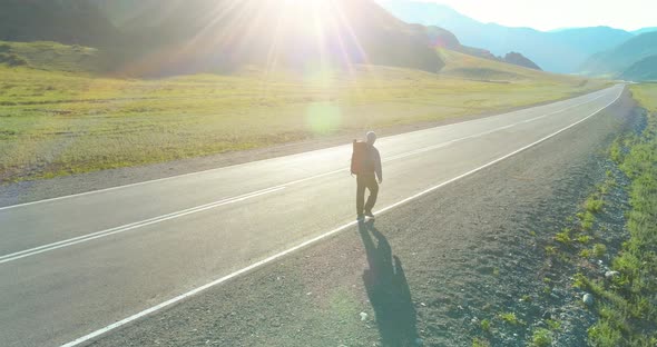 Flight Over Hitchhiker Tourist Walking on Asphalt Road. Huge Rural Valley at Summer Day