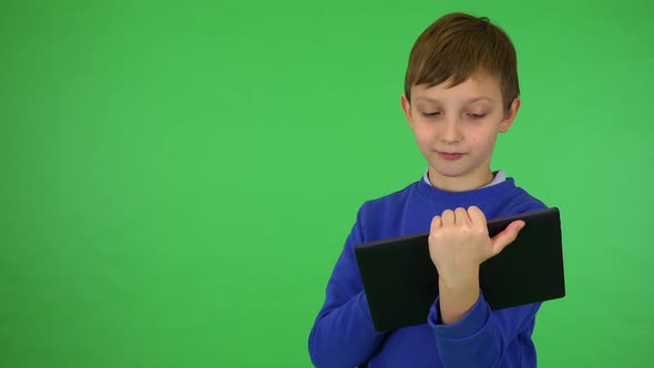 A Young Cute Boy Works on a Tablet - Green Screen Studio