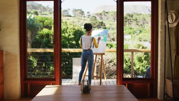 Mixed race woman painting on canvas in the balcony at home