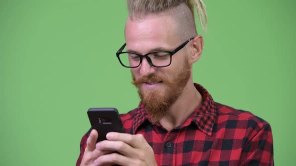 Happy Handsome Bearded Hipster Man with Dreadlocks Smiling While Using Phone