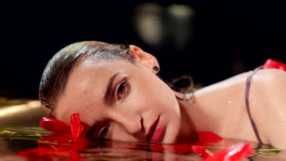 Tender and Seductive Lady is Lying in Water with Red Tulips Tempting and Mesmerizing Look