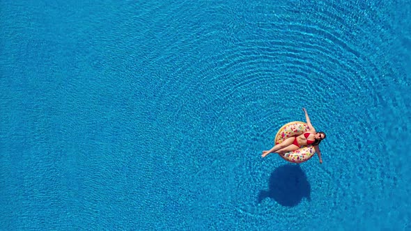 Aerial View of a Woman in Red Bikini Lying on a Donut in the Pool