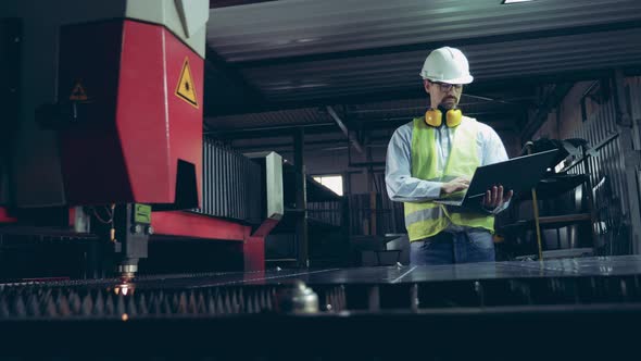 Industrial Laser Is Making Incisions on Metal Under Worker's Control