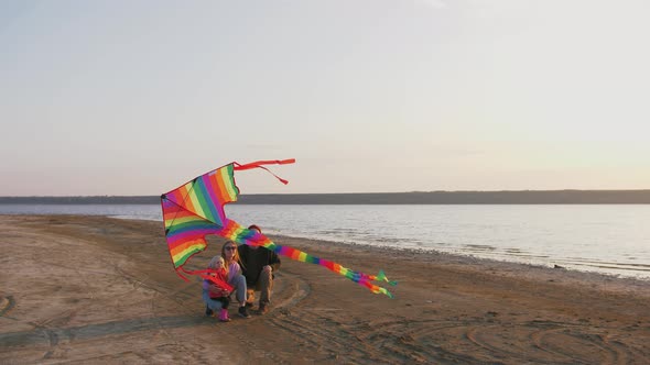 Happy Family with Flying Kite at the Seashore During Sunset Slow Motion