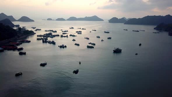 Port of Ha Long Bay Vietnam during sundown with dozens of commercial ships, Aerial flyover shot