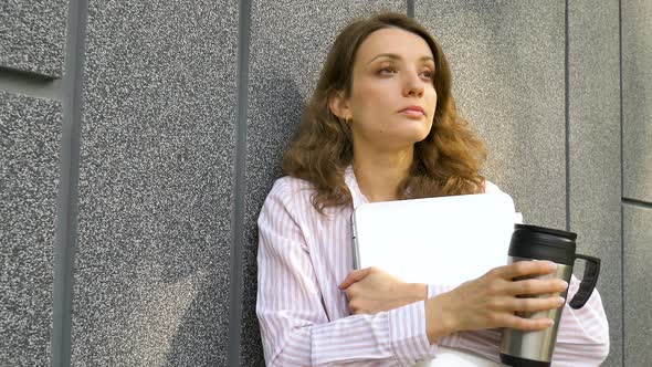 Female Portrait of Young Woman with Silver Laptop and Cup of Coffee Waiting for a Meeting Near Dark