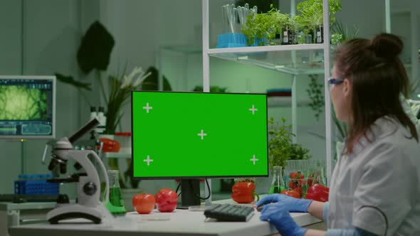 Pharmaceutical Researcher Looking at Computer with Mock Up Green Screen