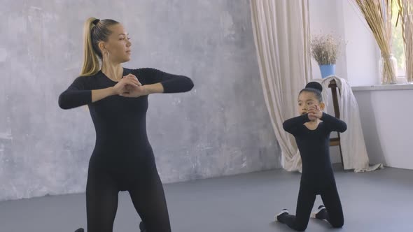 Little Asian Girl in Black Bodysuit Doing Dance Exercises with the Help of Female Trainer