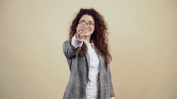 The Positive Young Woman with a Wide Smile Extends Her Hand in Front of Her to Get to Know Her