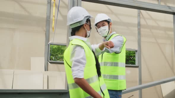 Asian workers people wearing face mask on site and make elbow bump in architecture due to covid 19.