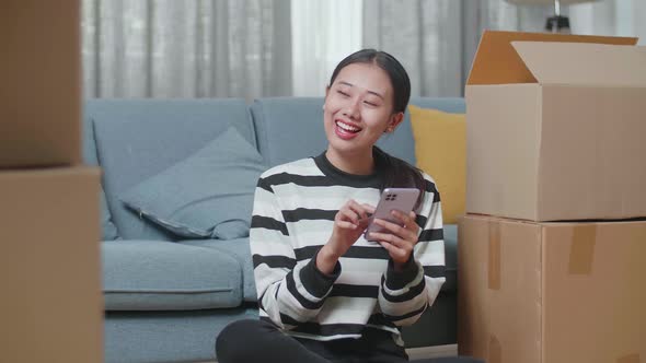 Asian Woman Comparing The House To The Photo On Smartphone After Moving Into A New House 