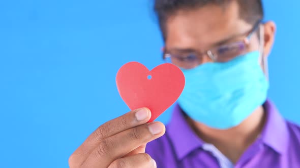 Young Happy Man Holding Red Heart on Blue Background 