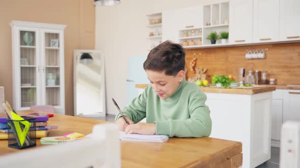 Boy In Kitchen Doing Homework And Chatting with Laptop on the Table