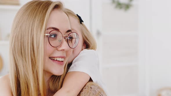 Portrait of Happy Young Mother Caucasian Woman in Glasses with Daughter Hugging at Home Talking