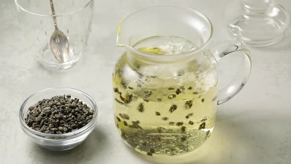   Pouring hot water in a glass teapot to make green gunpowder tea