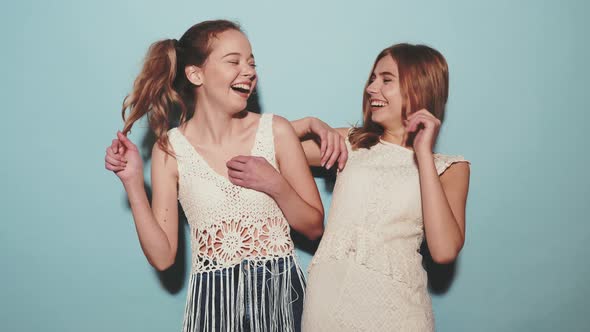 Two young beautiful smiling hipster girls in trendy summer white clothes
