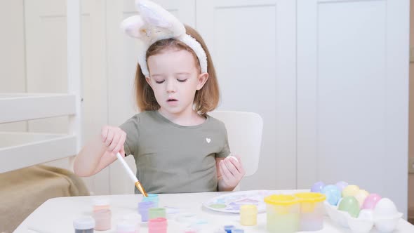 Little Girl in Easter Bunny Ears Painting Eggs