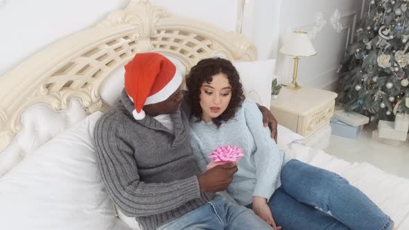 Young Couple with Christmas Gift in Bed at Home