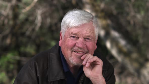 Older man with hand on chin cracking a smile.