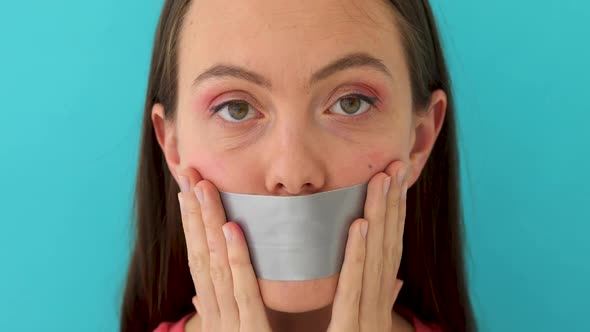 A Picture of a Young Girl with Her Lips Covered By a Tape Over Grey Background