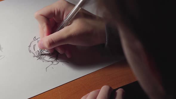 Close-up girls arm drawing a boy on a white paper by pen