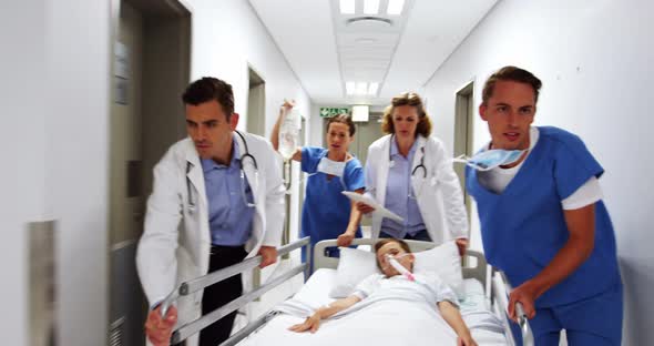 Doctors pushing emergency stretcher bed in corridor