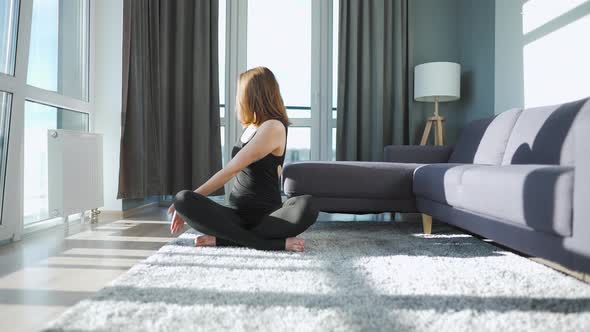 Young Caucasian Woman in Black Jumpsuit Doing Yoga at Home to Develop Flexibility and Balance