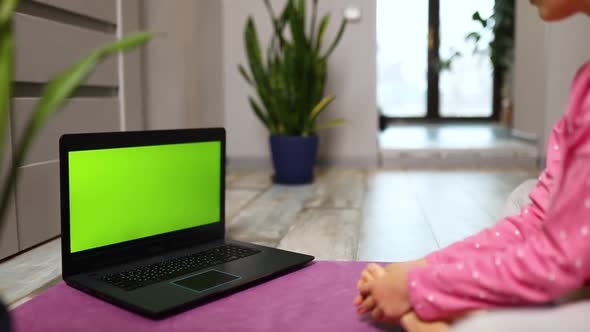 Little Girl Watching Online Video on Laptop and Doing Stretching Fitness Exercises at Home
