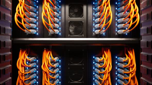 Countless orange cables in a  server cabinet lit by a single spotlight. 4KHD