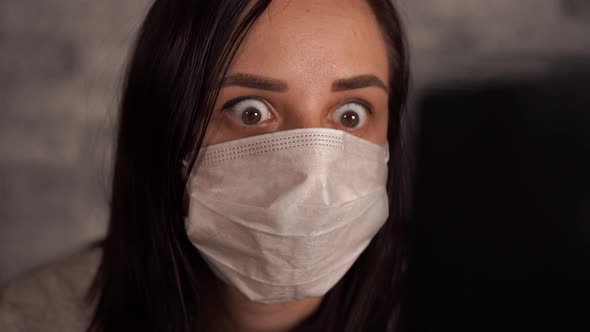 A Woman in a Medical Mask Learns News About the Coronavirus From the Internet Using a Laptop