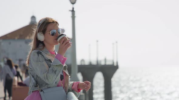 Happy Smiling Pretty Woman Enjoying Coffee at the Ocean Pier with Water View