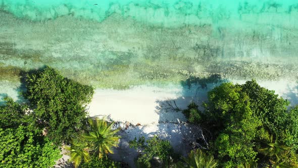 Wide angle overhead travel shot of a white sandy paradise beach and aqua turquoise water background 