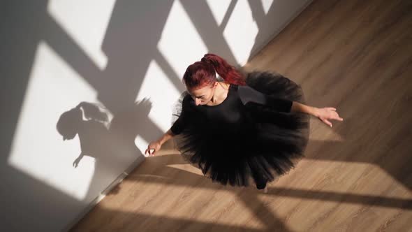 Ballerina in Black Tutu Gracefully Dances Against White Wall in Bright Sunlight