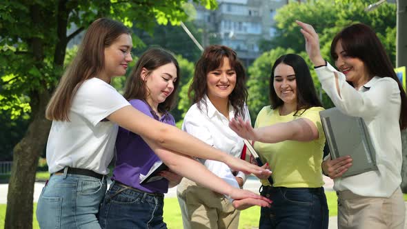 Multicultural Friends Stand in Circle Placing Their Raised Hands Together Centre